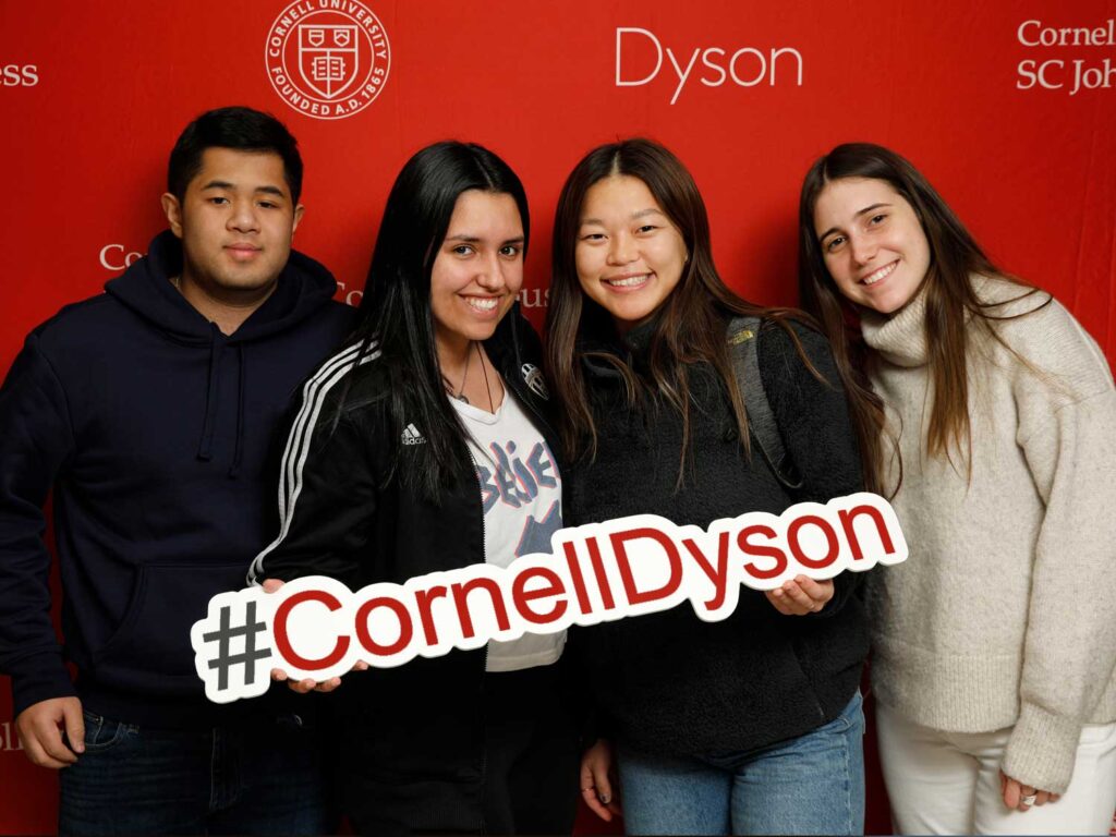 Four Dyson students pose with a “#CornellDyson” sign.