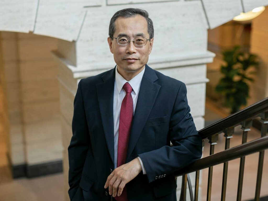 Dean Zhao standing on the stairs inside Warren Hall.