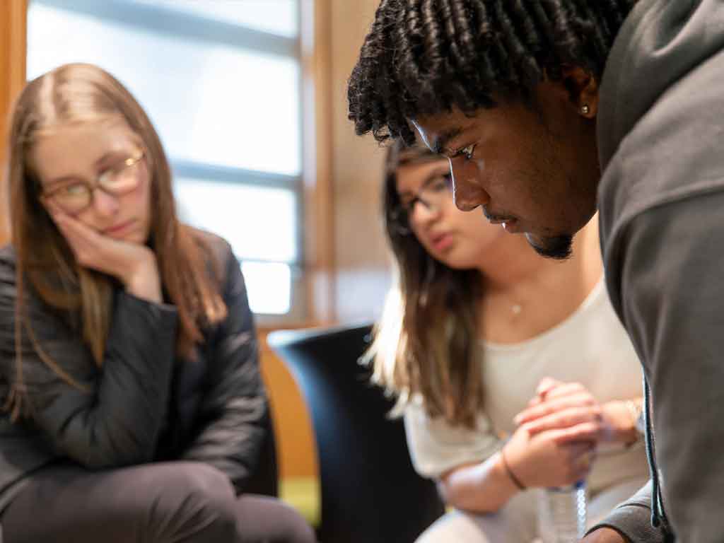 Three students look intently at something out of frame.