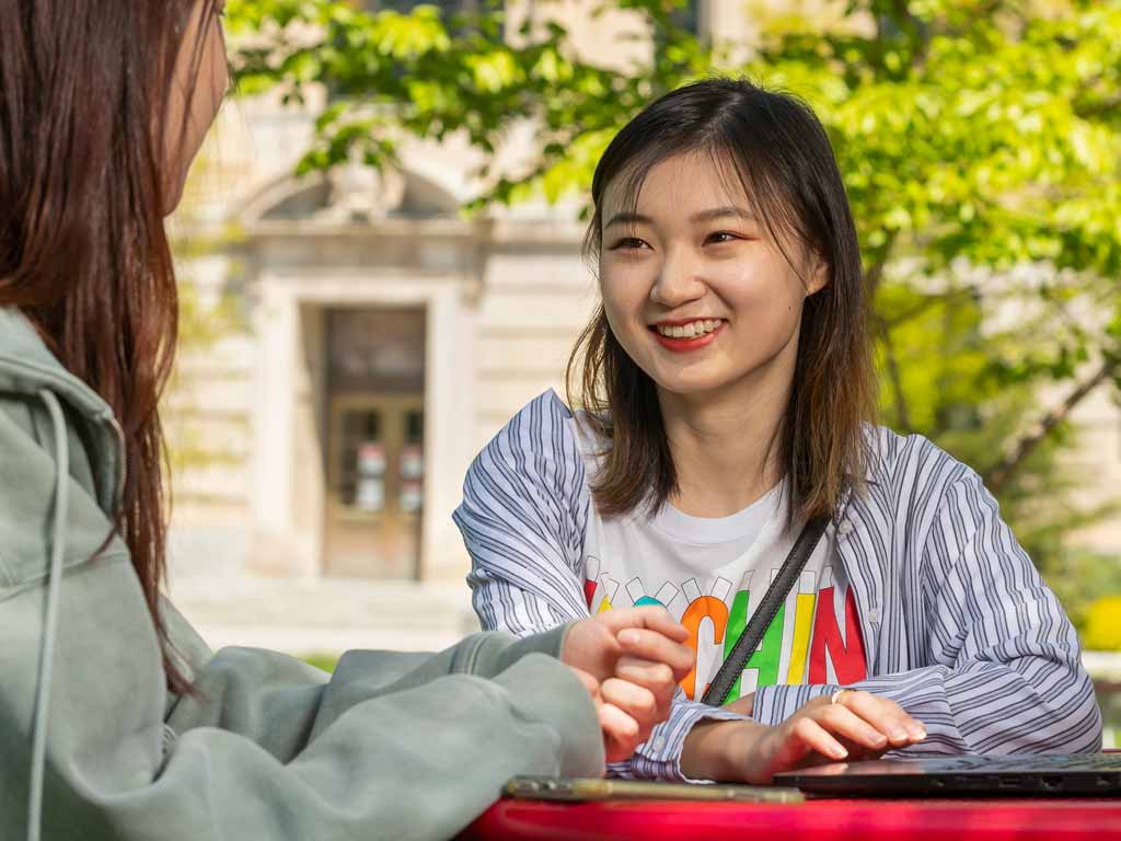 Two women sitting outside on the Ag Quad.