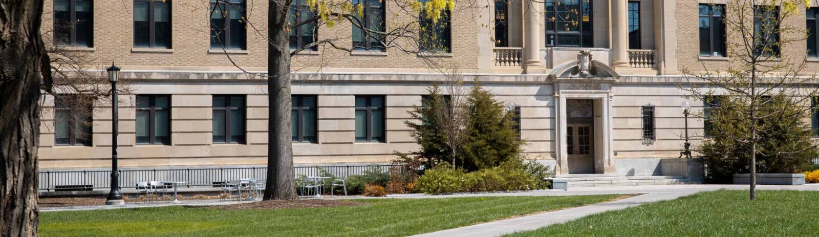 Outside of Warren Hall with a seating area, shrubbery, and a tree.